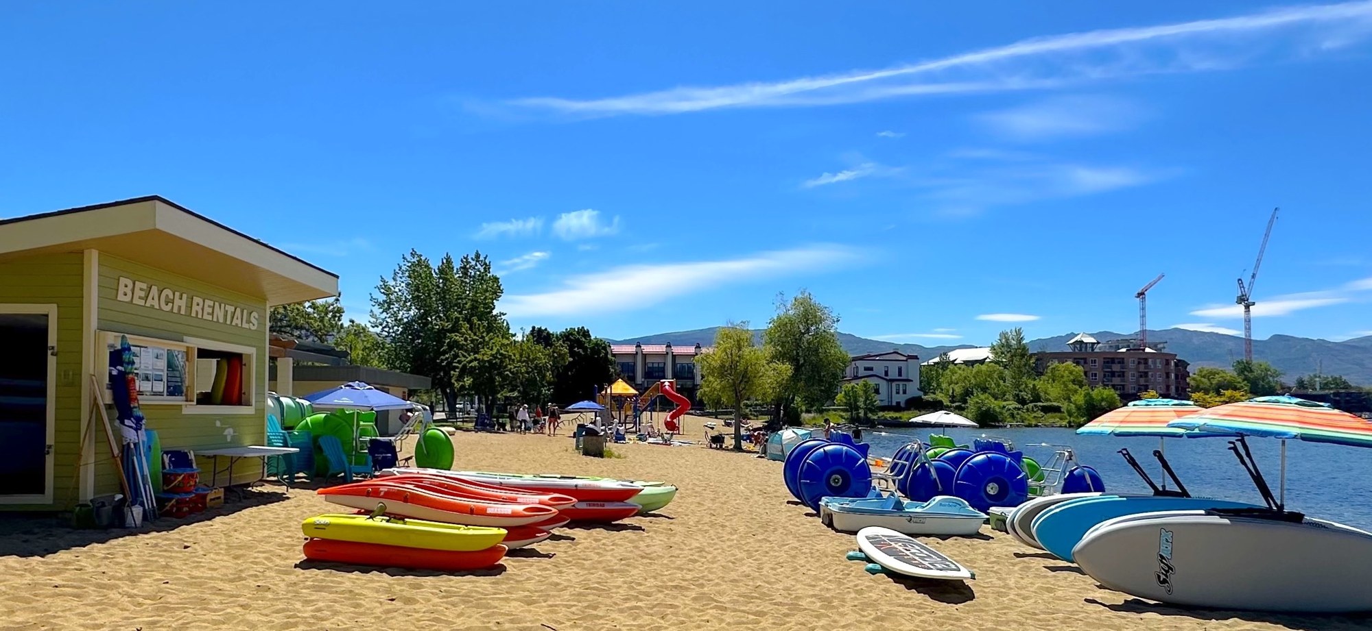Colourful kayaks and paddleboards waiting on the sand at Rotary Beach, Okanagan Lake